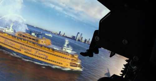 A view from a cockpit showing a Staten Island Ferry sailing in the water with a city skyline in the background.