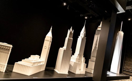 A display of white architectural models of famous skyscrapers against a black background.
