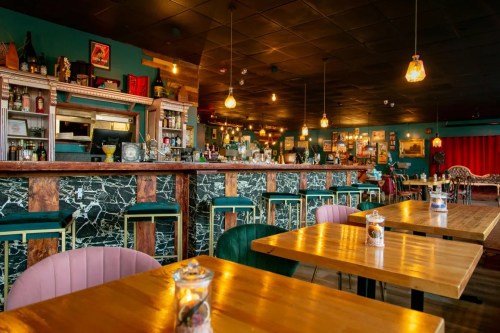 A stylish bar interior with wooden tables, a marble counter, and warm lighting, creating a cozy atmosphere.