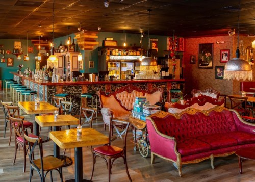 A cozy bar with vintage decor, featuring plush seating, wooden tables, and a well-stocked bar in a warm atmosphere.