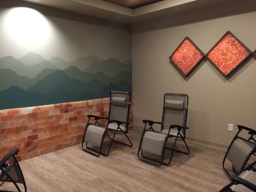 A serene room with reclining chairs, a salt wall, and a mountain mural, creating a calming atmosphere.
