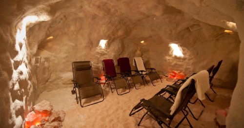 A cozy salt room with reclining chairs, soft lighting, and salt crystals on the floor, creating a relaxing atmosphere.