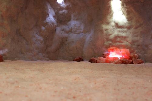 A serene cave-like space with soft, sandy ground and glowing pink salt crystals illuminated by soft lights.