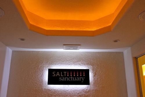 A well-lit entrance to a spa or wellness center, featuring a sign that reads "SALT sanctuary" against a textured wall.