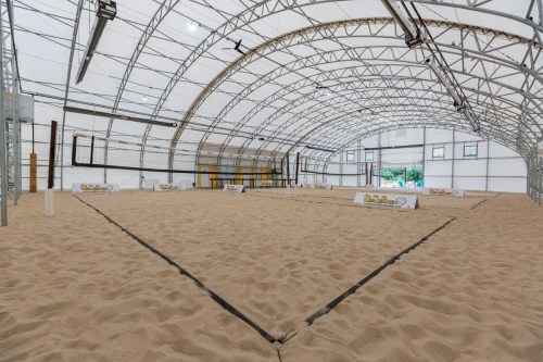 Indoor sand volleyball court with a large, arched structure and banners along the sides.