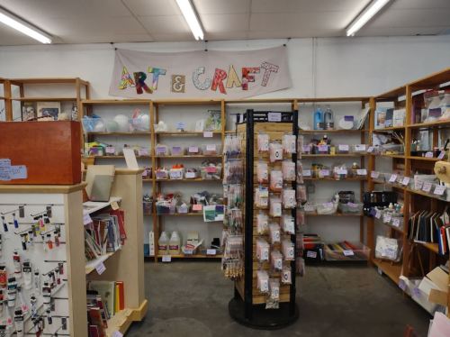 A craft store interior featuring shelves of art supplies and a banner reading "ART & CRAFT."