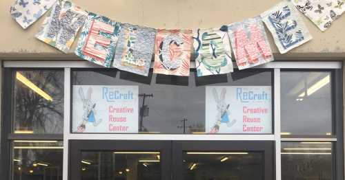 A storefront with a "Welcome" banner and signs for "ReCraft Creative Reuse Center" featuring a cartoon bunny.