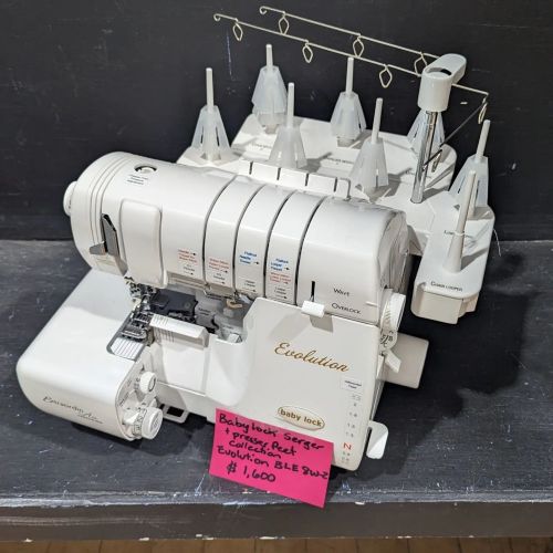 A Baby Lock Evolution serger sewing machine displayed on a table with a price tag of $1,600.
