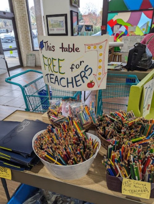A table with a sign reading "Free for Teachers" surrounded by colorful pencils and school supplies.