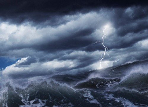 A stormy ocean scene with dark clouds and a bright lightning bolt striking above turbulent waves.