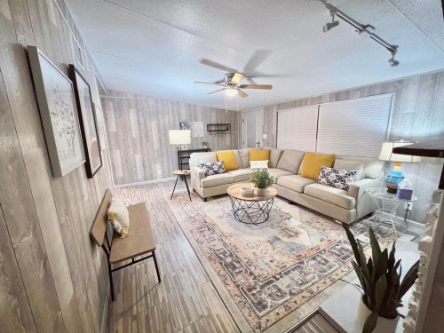 Cozy living room with a sectional sofa, decorative pillows, a coffee table, and a patterned rug against wooden walls.