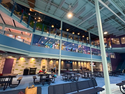 Interior view of a spacious recreational facility with multiple levels, seating areas, and colorful decor.