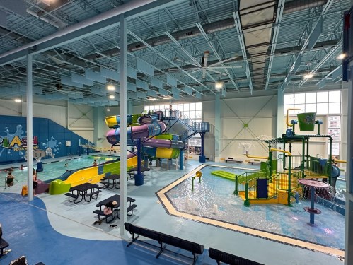 Indoor water park featuring colorful slides, splash pads, and a pool area with families enjoying the attractions.