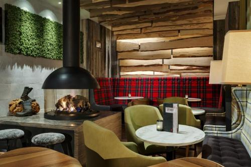 Cozy restaurant interior featuring a fireplace, wooden accents, plaid seating, and stylish tables.