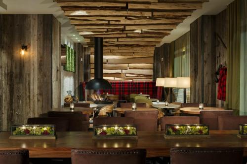 Cozy restaurant interior with wooden decor, a fireplace, and tables adorned with greenery. Warm, inviting atmosphere.
