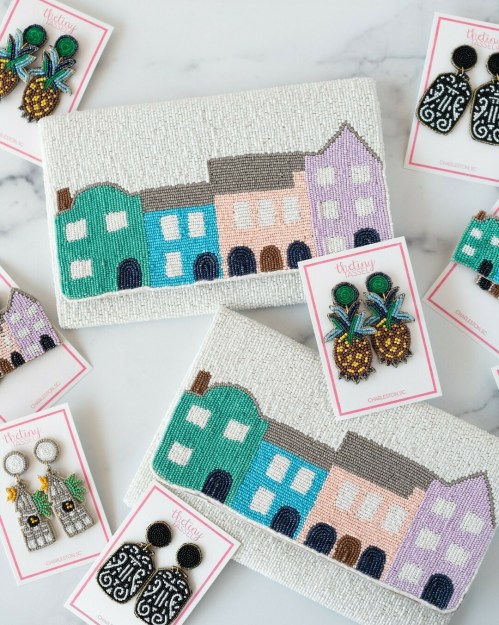Colorful beaded clutches with pastel houses, paired with vibrant pineapple and house-shaped earrings on display.