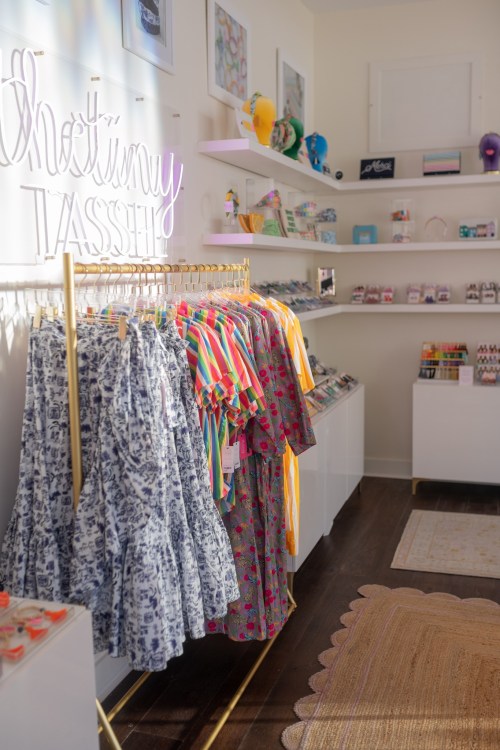 A boutique interior featuring colorful dresses on racks and various accessories displayed on shelves.