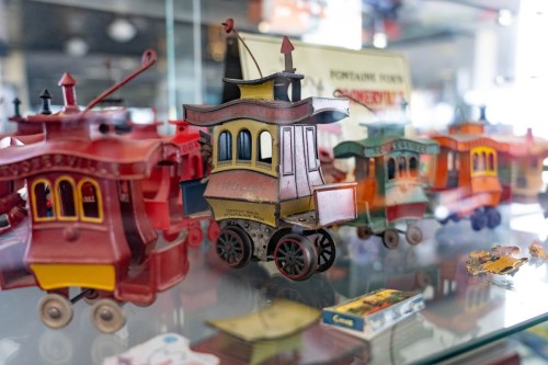 Colorful vintage toy trains displayed in a glass case, showcasing intricate designs and details.