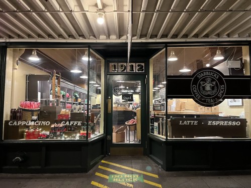 A Starbucks storefront at night, featuring large windows displaying coffee products and a welcoming entrance.
