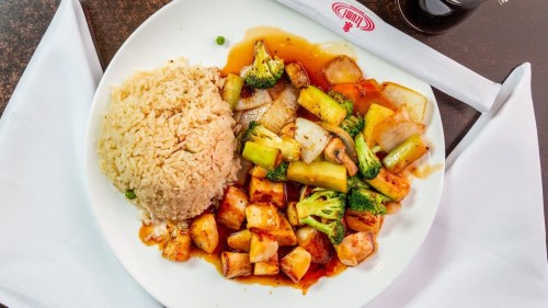A plate of stir-fried vegetables with rice, featuring broccoli, zucchini, and a savory sauce.