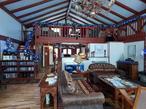 Cozy interior of a decorated lodge with wooden beams, festive lights, and a warm seating area.