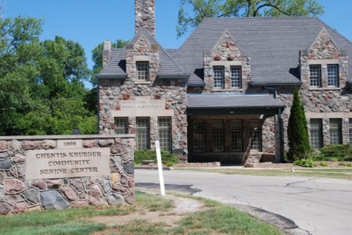 Stone building with a steep roof and multiple windows, featuring a sign for the Chents-Krueger Community Senior Center.
