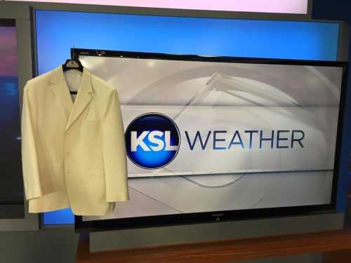 A white suit jacket hangs next to a KSL Weather graphic on a television screen.