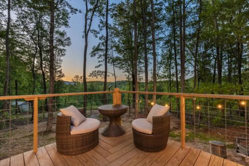 Cozy outdoor seating area with two chairs and a table, surrounded by trees and a sunset view.