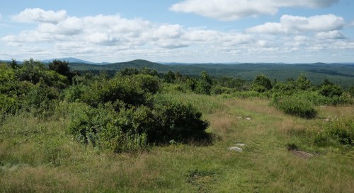 A scenic view of rolling hills and lush greenery under a partly cloudy sky.