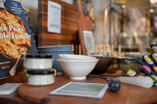A cozy kitchen scene featuring bowls, cookbooks, and utensils on a wooden surface.