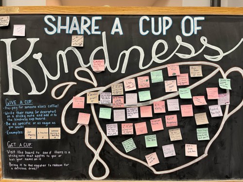 Chalkboard sign promoting "Share a Cup of Kindness" with sticky notes for giving and receiving kindness.