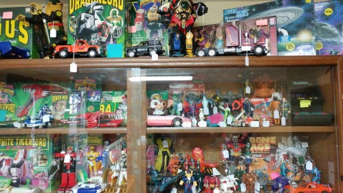 A display case filled with vintage toys, including action figures, vehicles, and collectibles from various franchises.