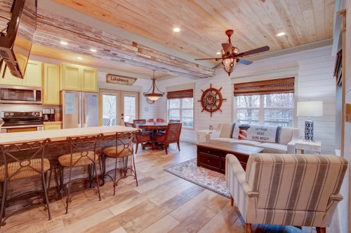 Cozy kitchen and dining area with wooden accents, a ship wheel decor, and comfortable seating in a bright, inviting space.
