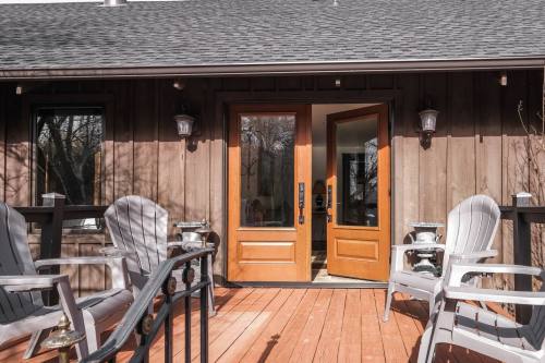 A wooden deck with two chairs in front of double doors leading into a cozy interior space.
