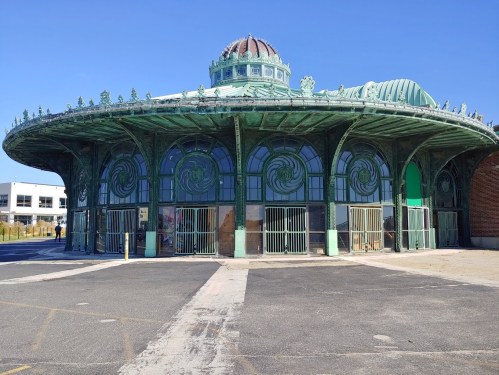 Historic green pavilion with ornate architecture, featuring large windows and a domed roof, set against a clear blue sky.