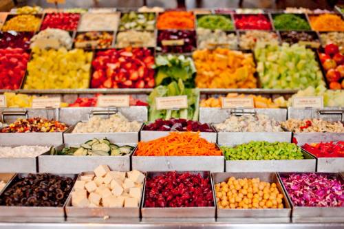 A vibrant display of fresh fruits and vegetables in bins, showcasing a variety of colors and textures.