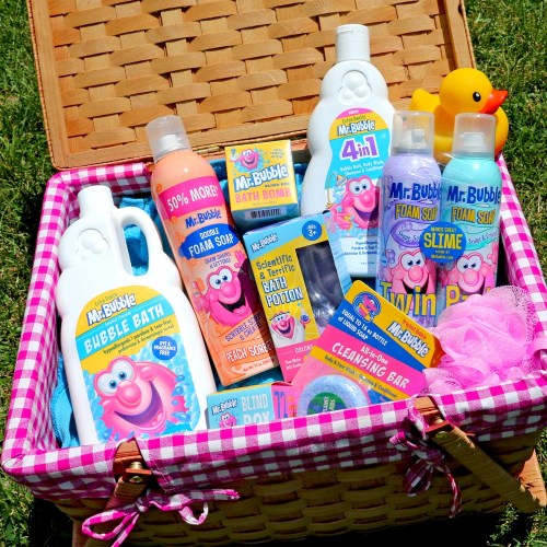A picnic basket filled with various Mr. Bubble bath products, a rubber duck, and a loofah on a grassy background.
