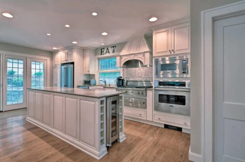 Modern kitchen with white cabinetry, stainless steel appliances, and a large island with a countertop. Bright and spacious design.