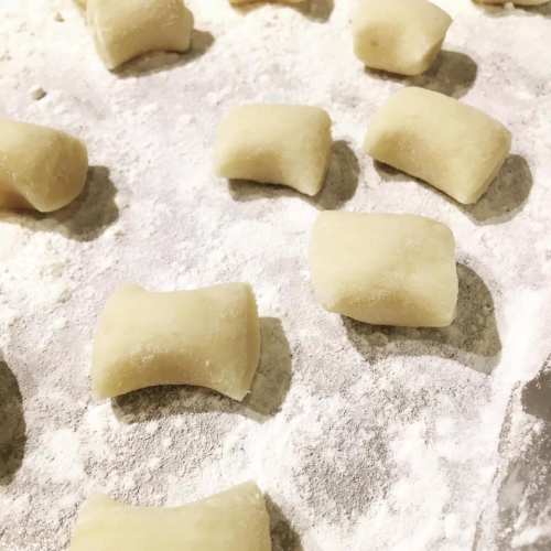 Freshly shaped gnocchi pieces resting on a floured surface, ready for cooking.