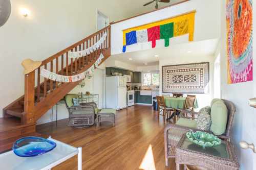 Bright, airy living space with wooden stairs, colorful decor, and a cozy dining area.