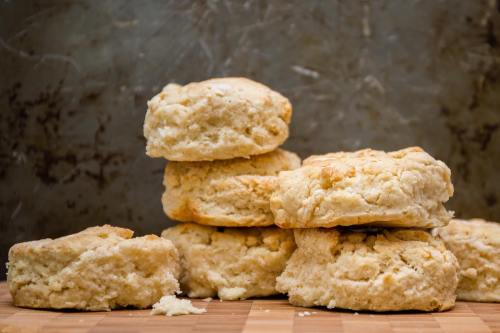 A stack of freshly baked biscuits on a wooden surface, with a rustic background.