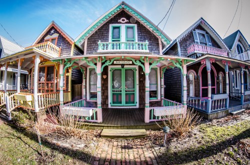 Colorful Victorian-style houses with intricate woodwork and porches, set against a clear blue sky.