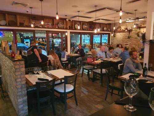 A bustling restaurant interior with diners at tables, warm lighting, and a cozy atmosphere.