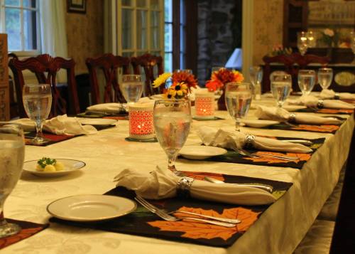 A beautifully set dining table with glasses, plates, and floral centerpieces, ready for a meal.