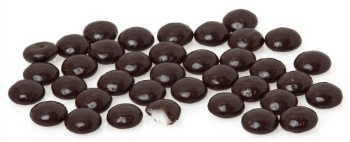 A scattered pile of dark chocolate-covered candies, with one candy partially bitten to reveal a white filling.