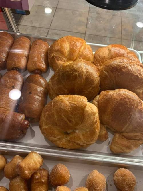A display case filled with various baked goods, including croissants and sweet rolls.