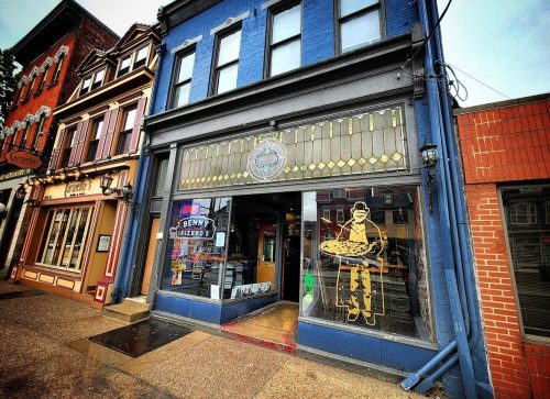 A colorful storefront featuring a large window display with a cartoonish figure holding a pizza.