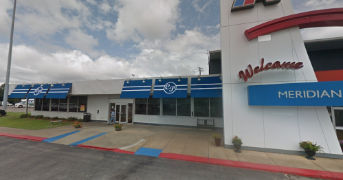 Exterior view of a restaurant with blue awnings and a "Welcome" sign, set against a cloudy sky.