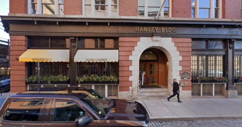 Exterior view of the Hanley Building, featuring a restaurant with awnings and a pedestrian walking by.