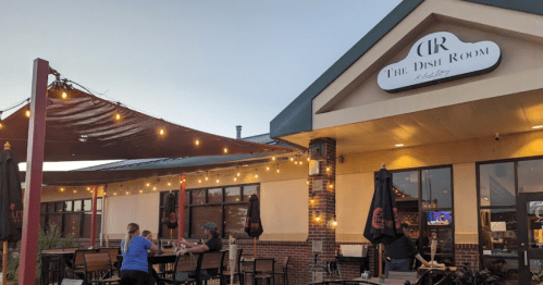 Exterior of The Dish Room restaurant with outdoor seating, string lights, and a warm evening ambiance.